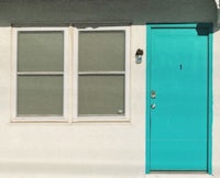 a turquoise door on a white building